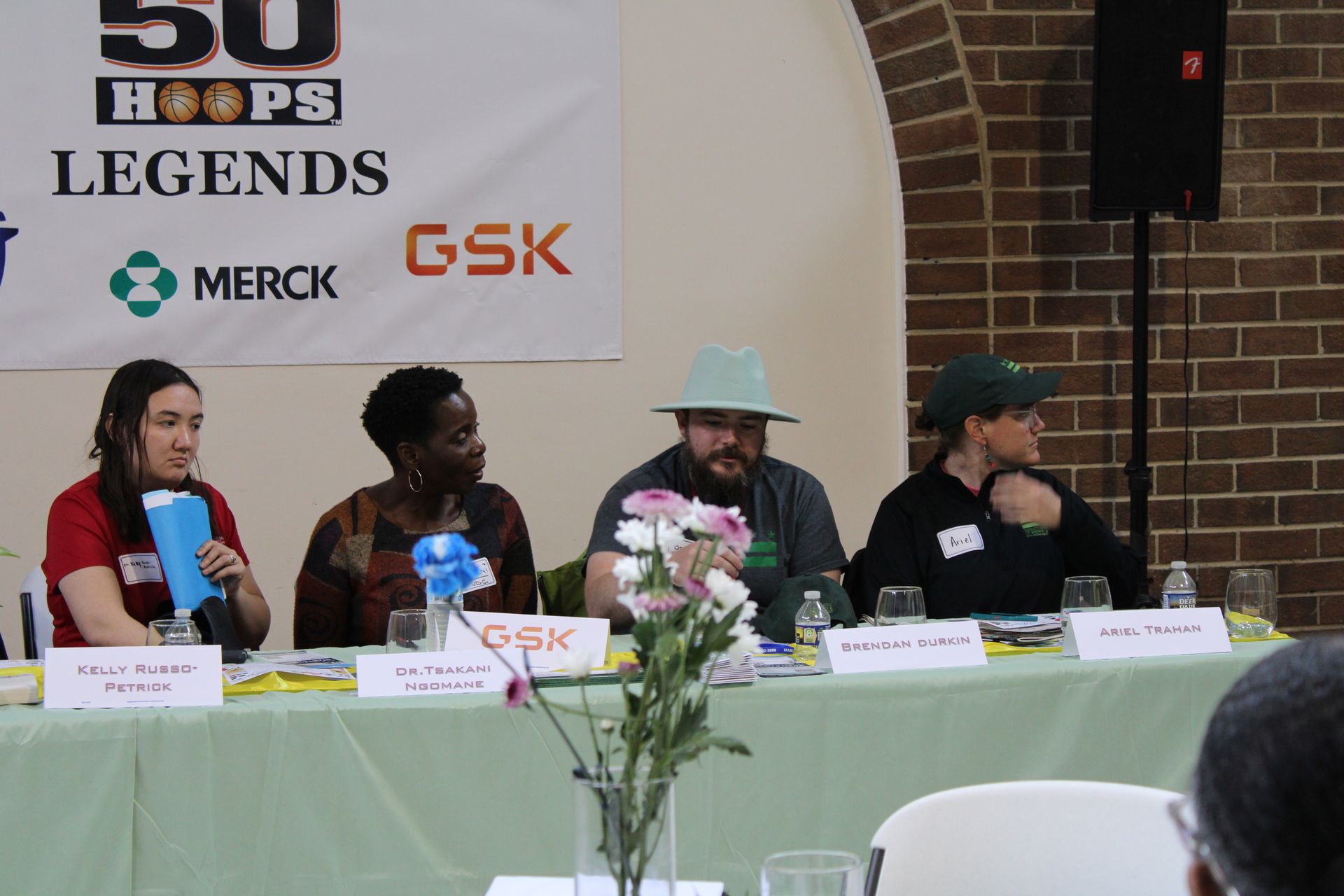 Panel discussion at a table with four people, under a banner. Sponsors logos visible.