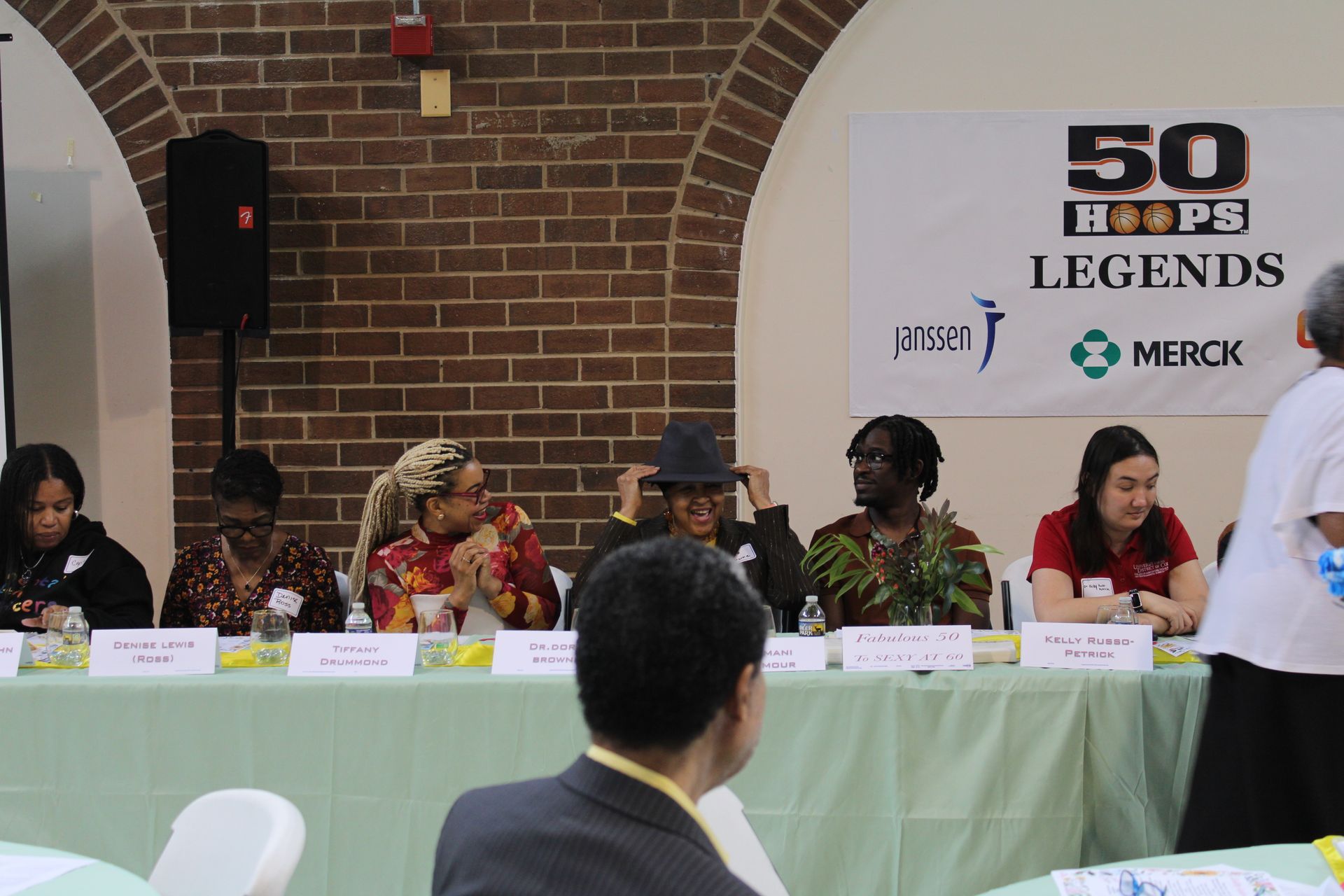 Panel of people seated at a table with a banner that reads 