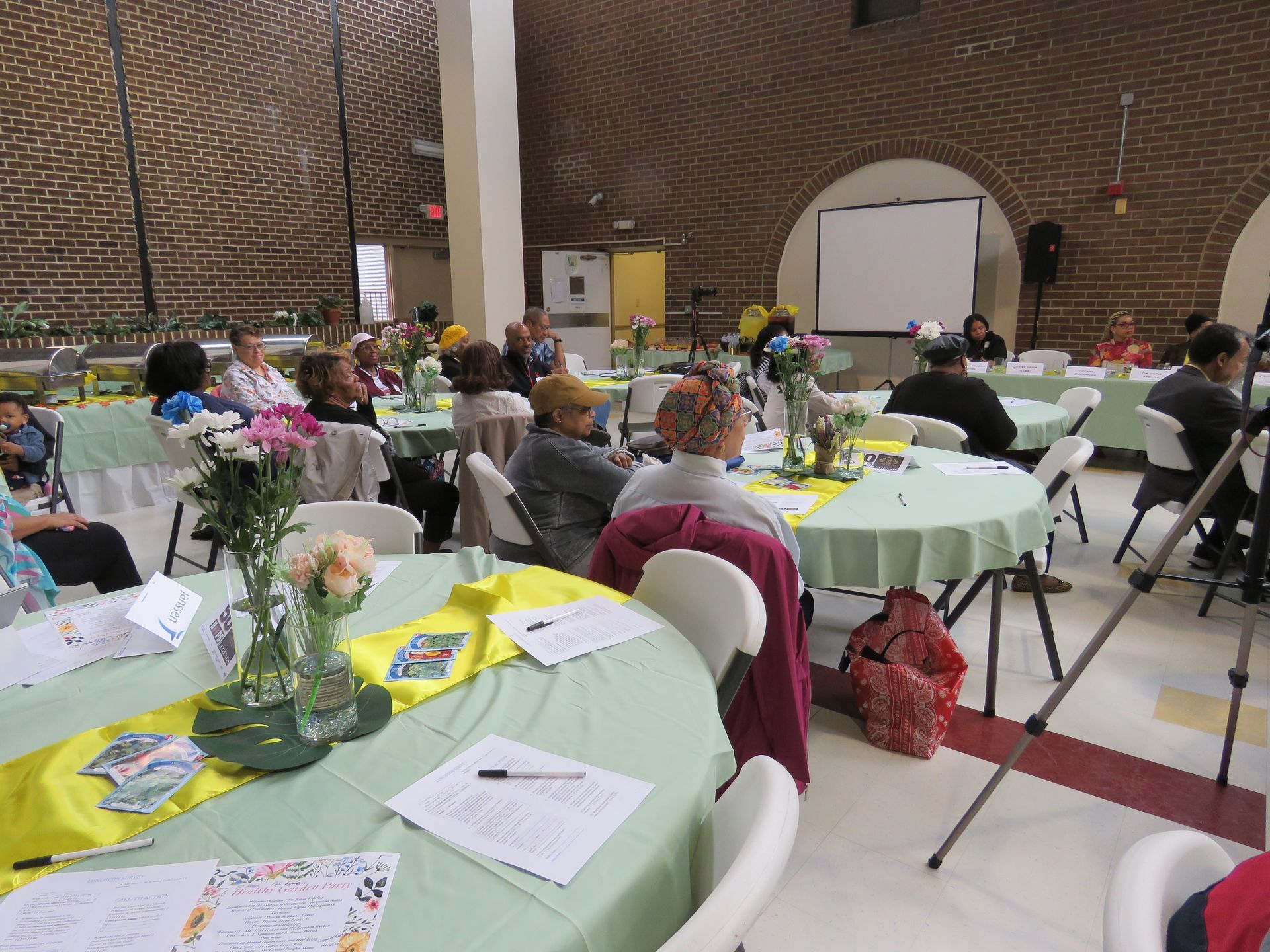 People seated at round tables in a large room, attending an event.