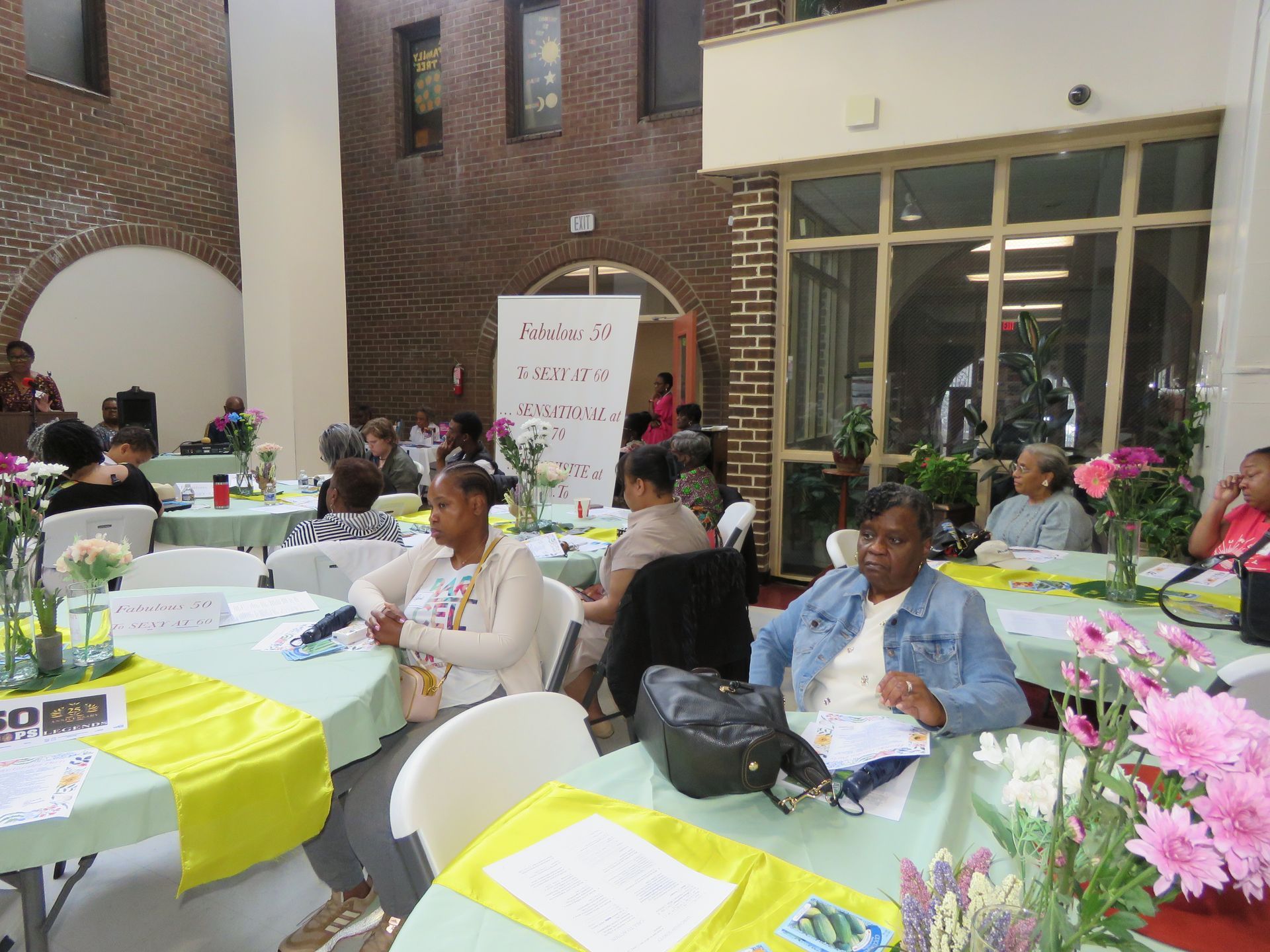 People seated at tables in a room, attending an event. 