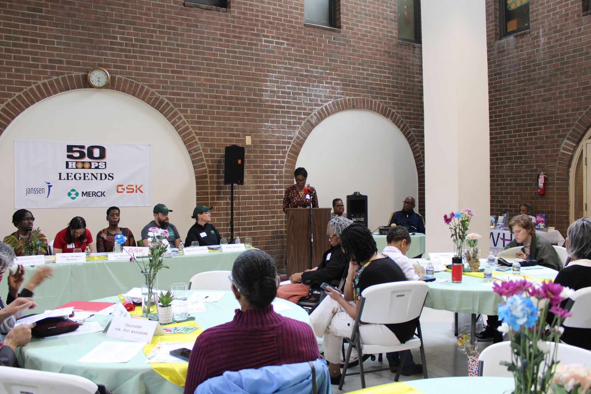 People at a panel discussion, some seated at a table, others in the audience. 
