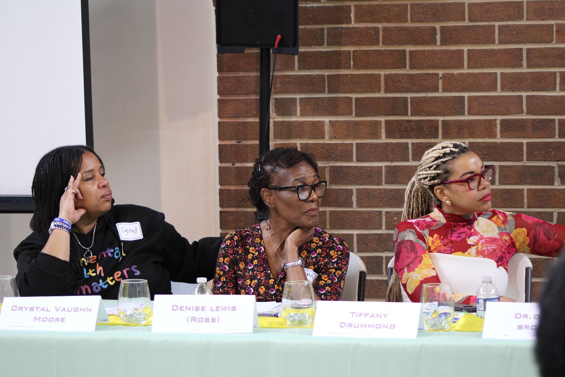 Panel of three women seated at a table, discussing issues at an event.