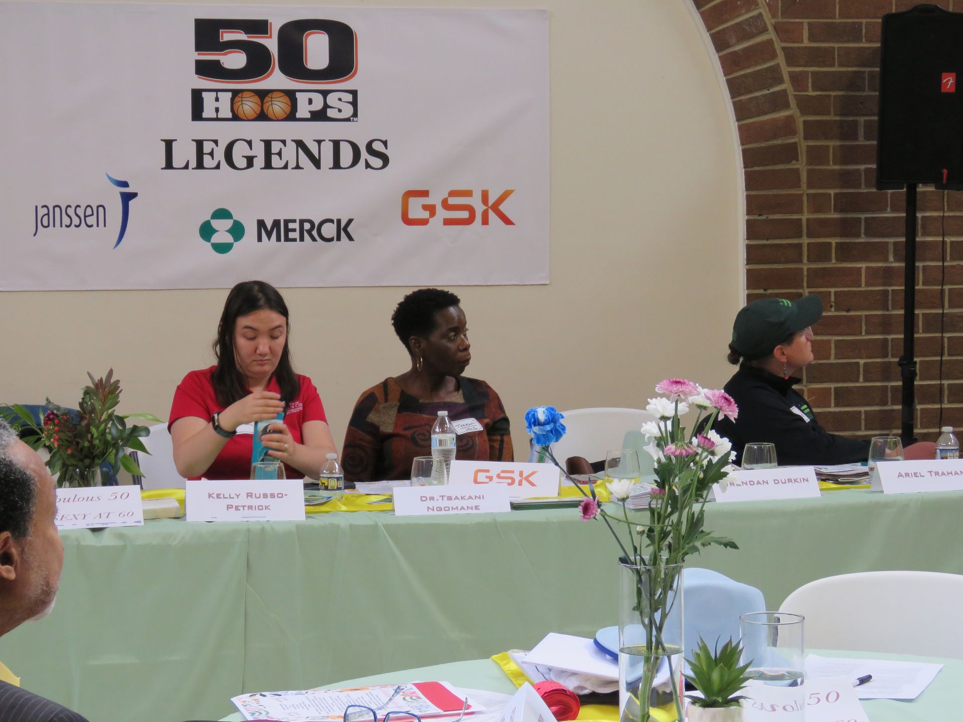 Panel with three people seated at a table, with a banner that says 