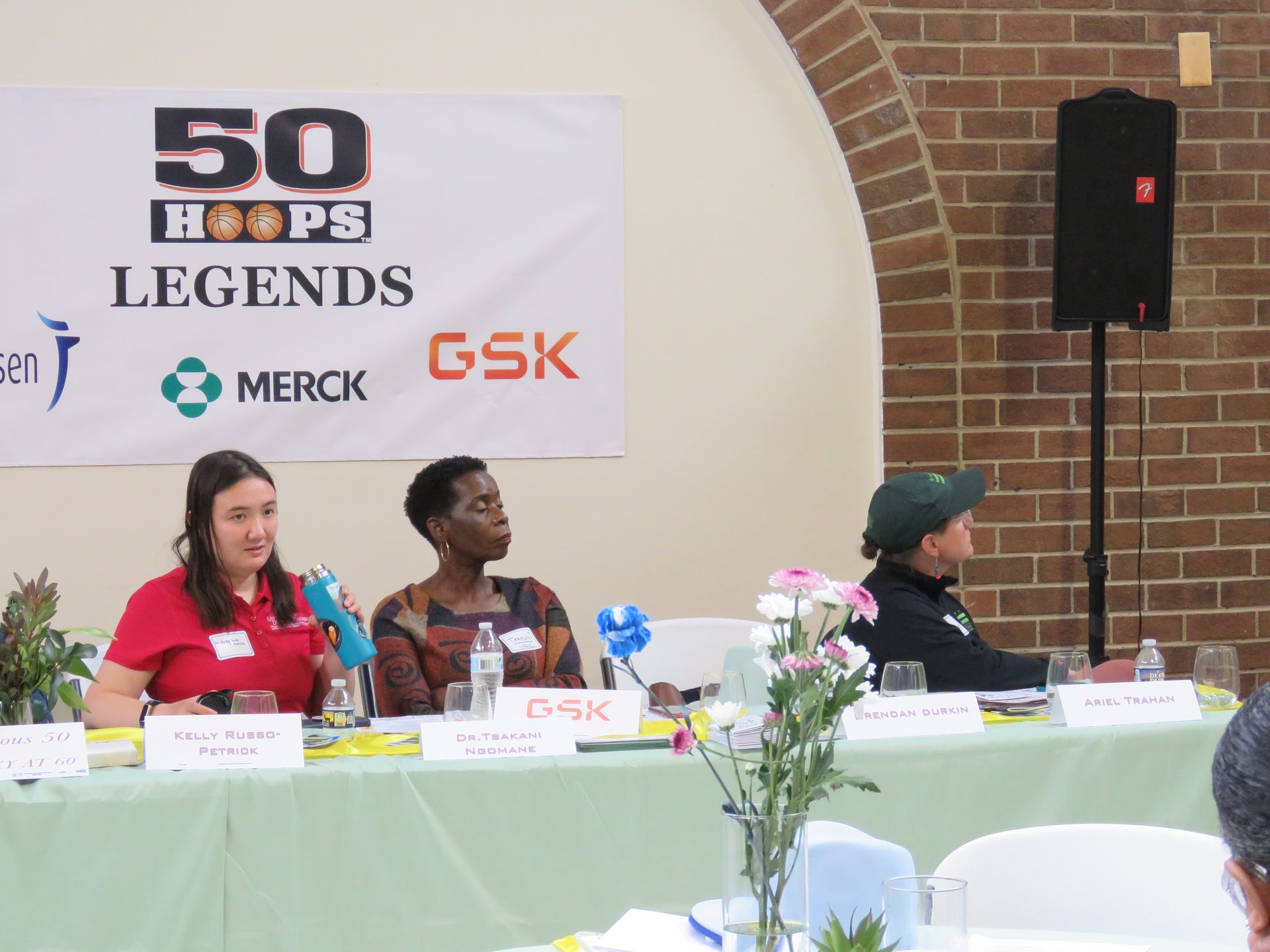 Panel of three speakers at a conference with a banner that reads 