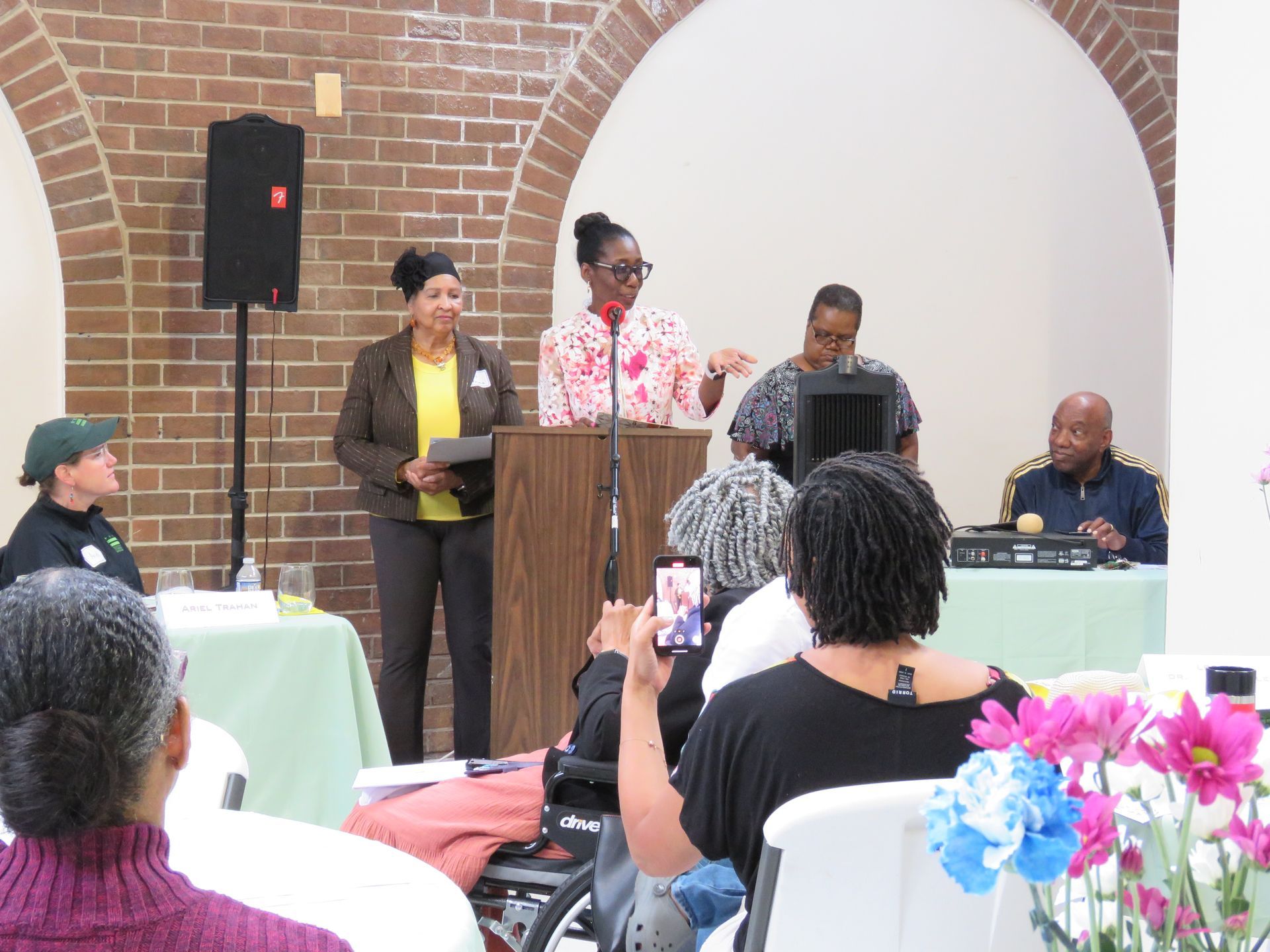 Panel discussion at a community event; people speaking at a podium and table.