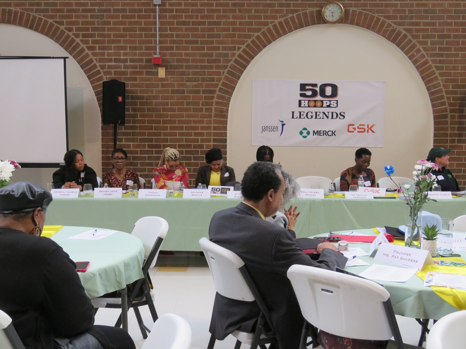 Panel of people at a conference table, banner reading 