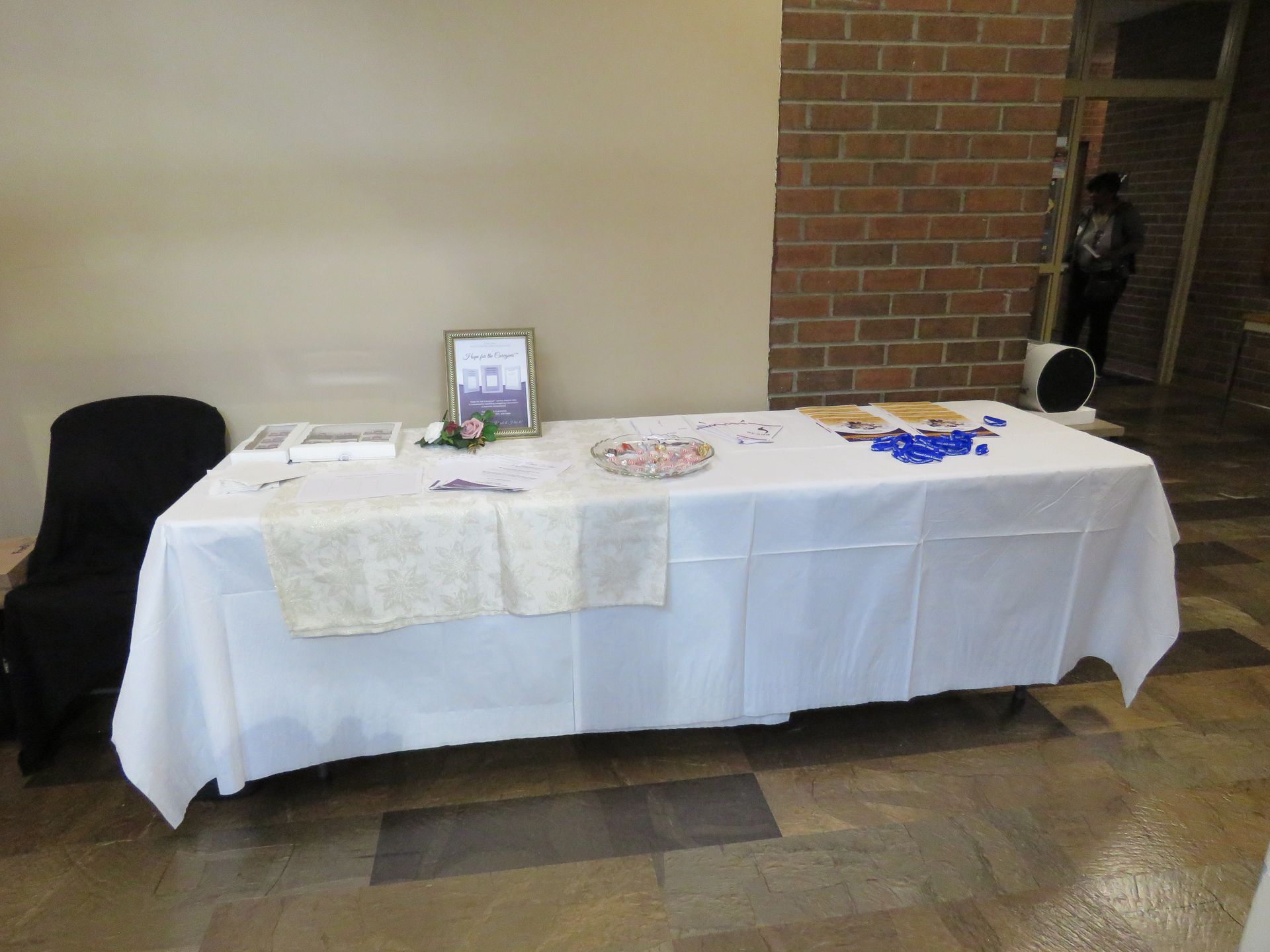 Table with white tablecloth and items displayed on it, set up against a wall.