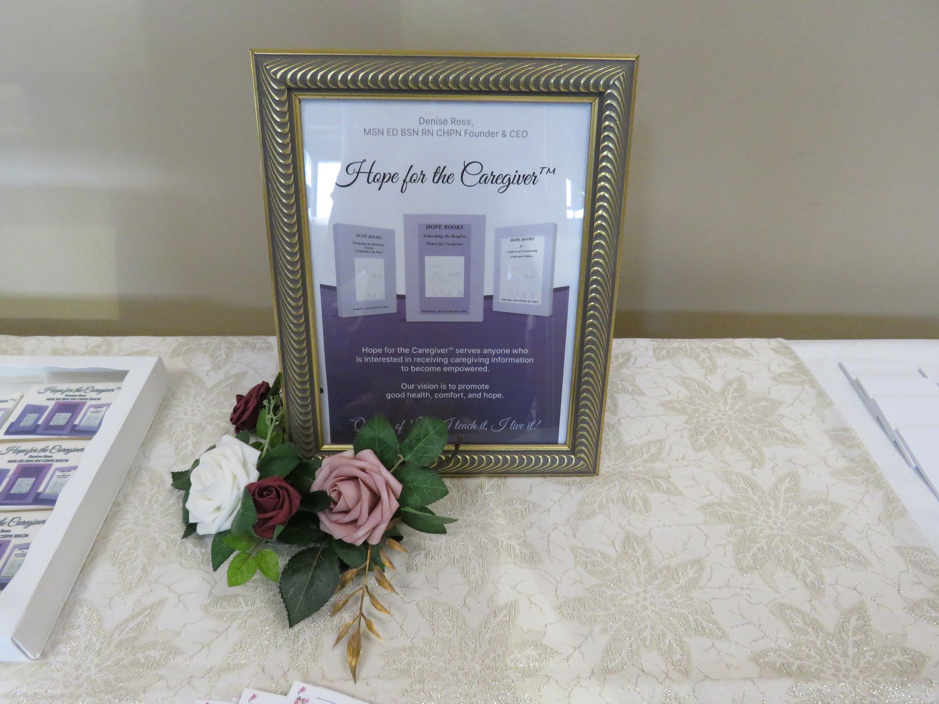 Gold-framed sign with floral arrangement. Sign promotes 