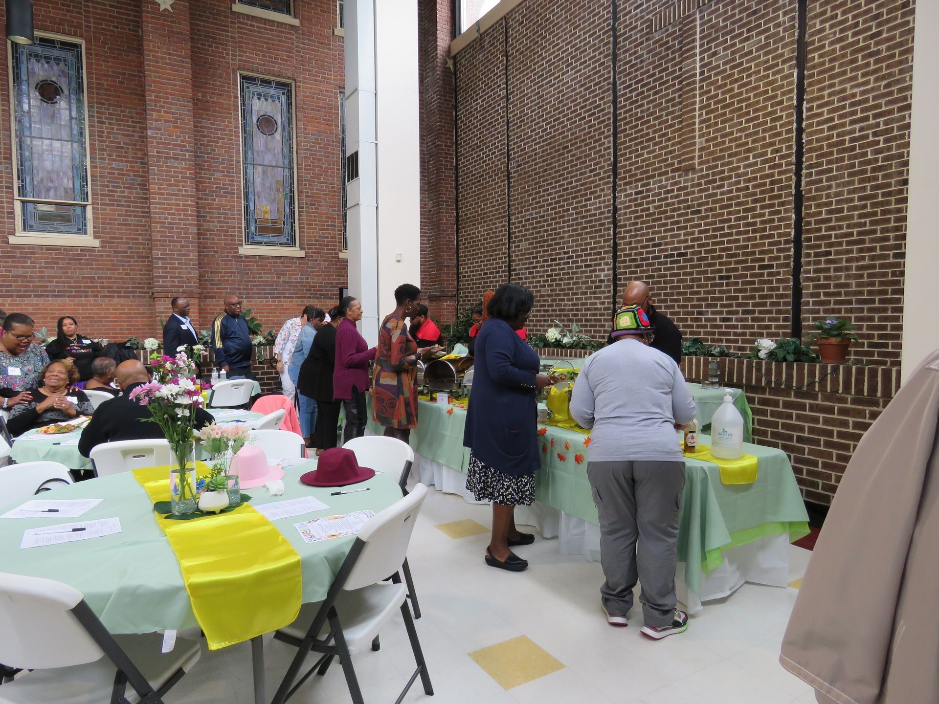 People at a reception with tables, food, and brick walls.