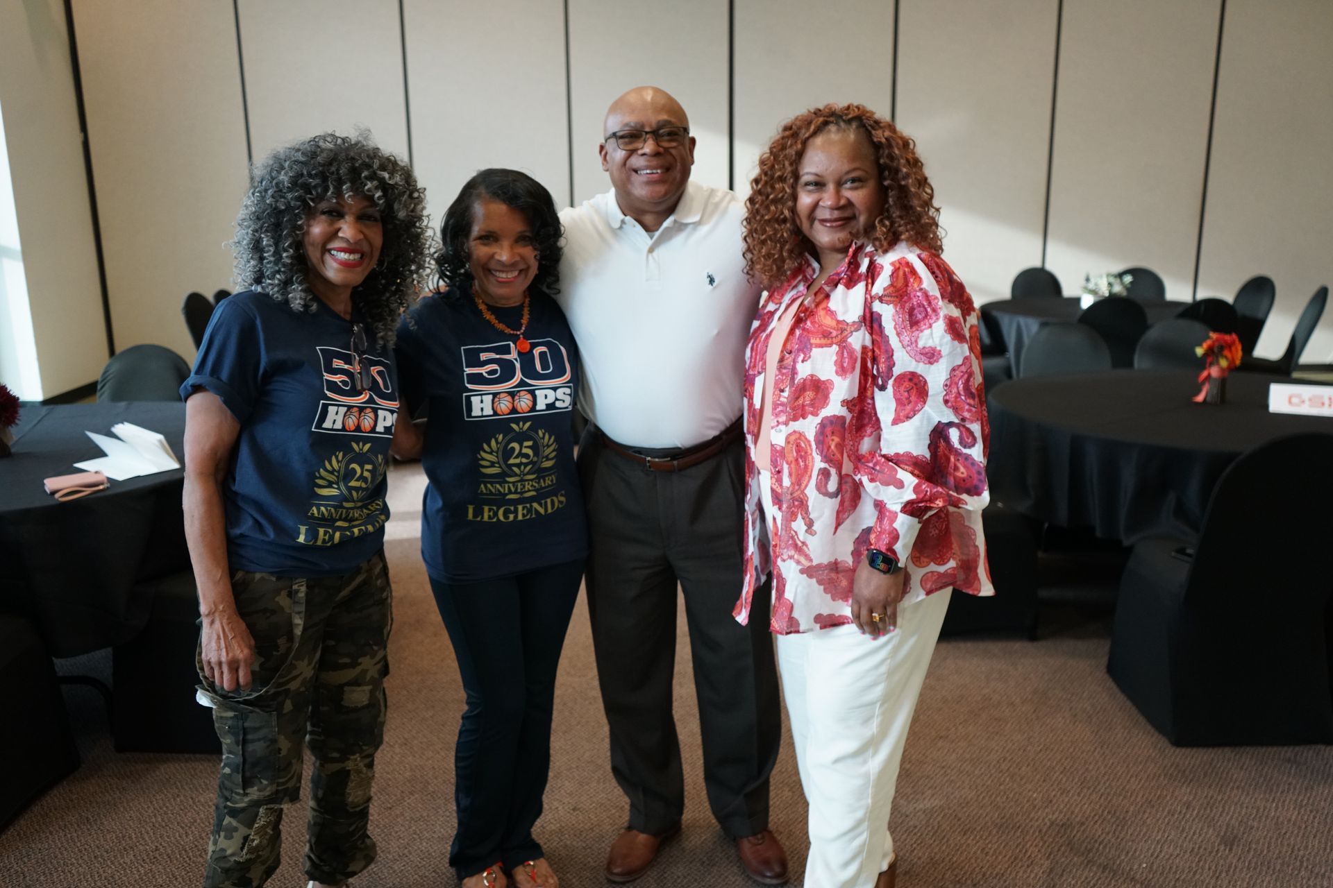 Four people pose for a photo in a room. 