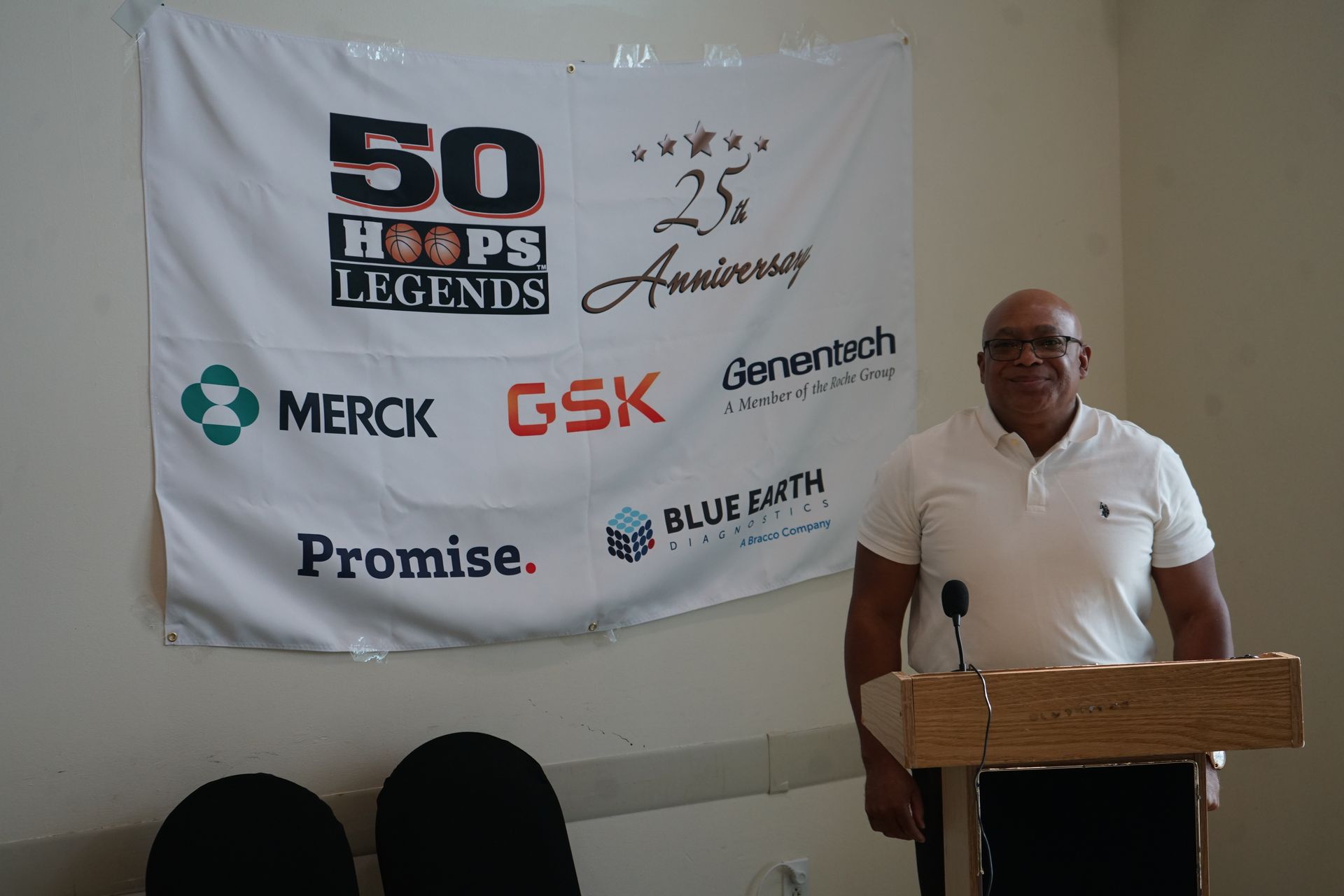 Man standing at a podium in front of a banner with text and company logos.
