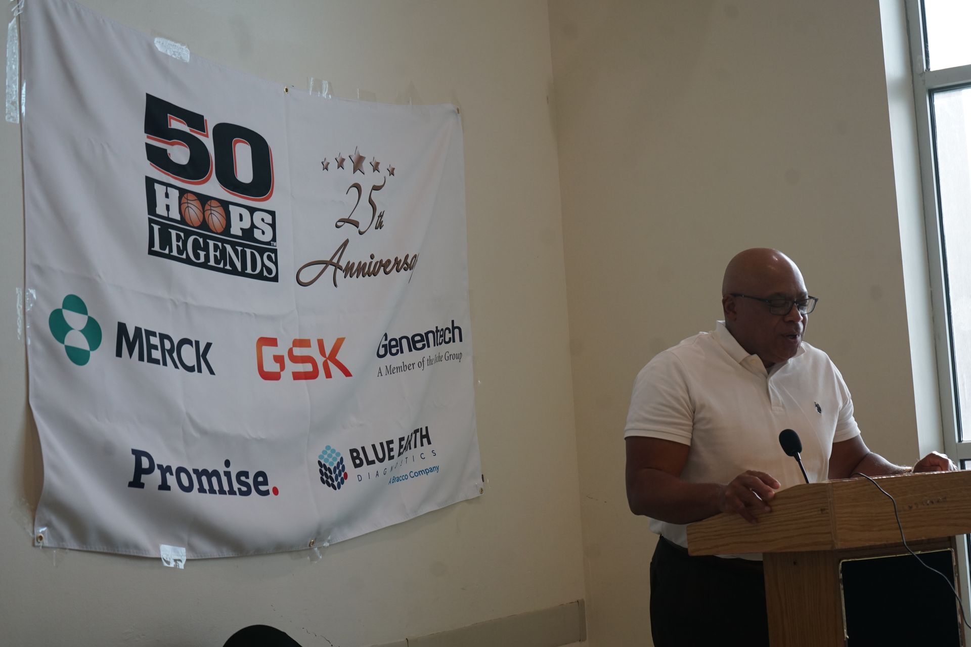 Man speaking at a podium in front of a banner for the 