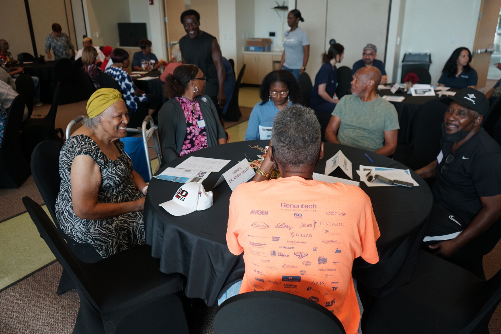 People seated around a round table in a meeting room, engaged in conversation.