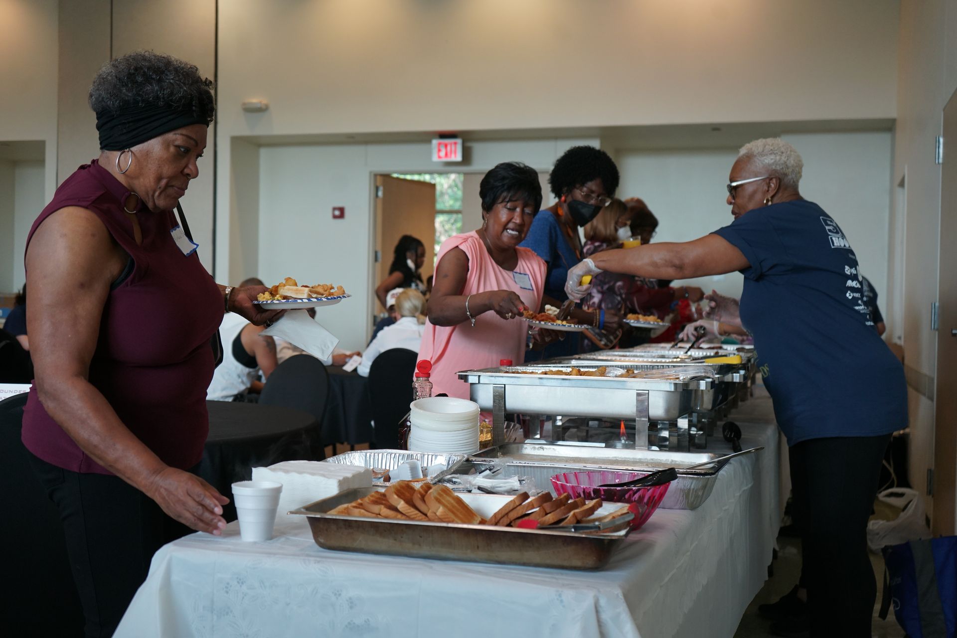 People serving themselves food from a buffet table at an event.