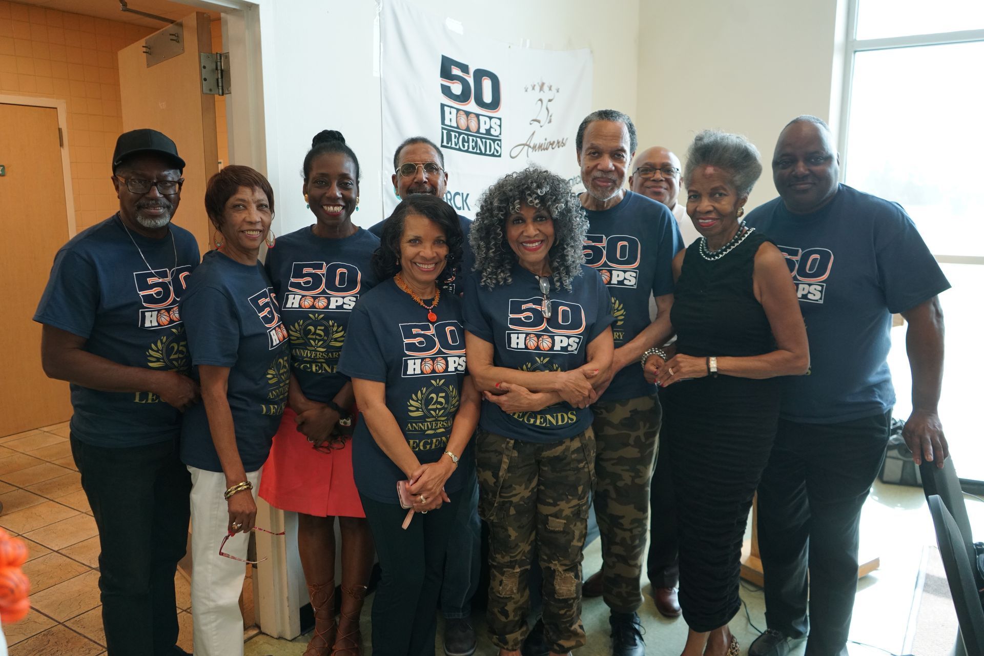 Group of people in matching shirts posing near a banner that says 