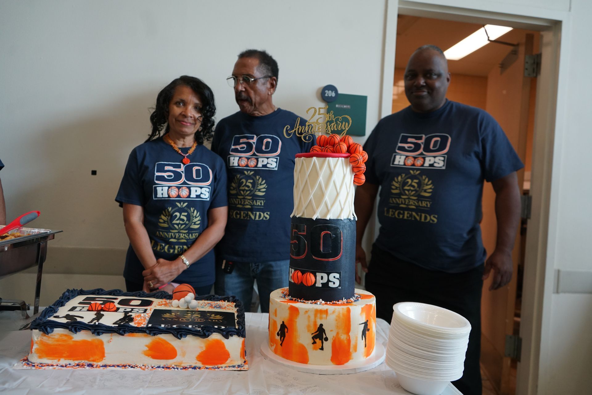 Three people pose with two cakes