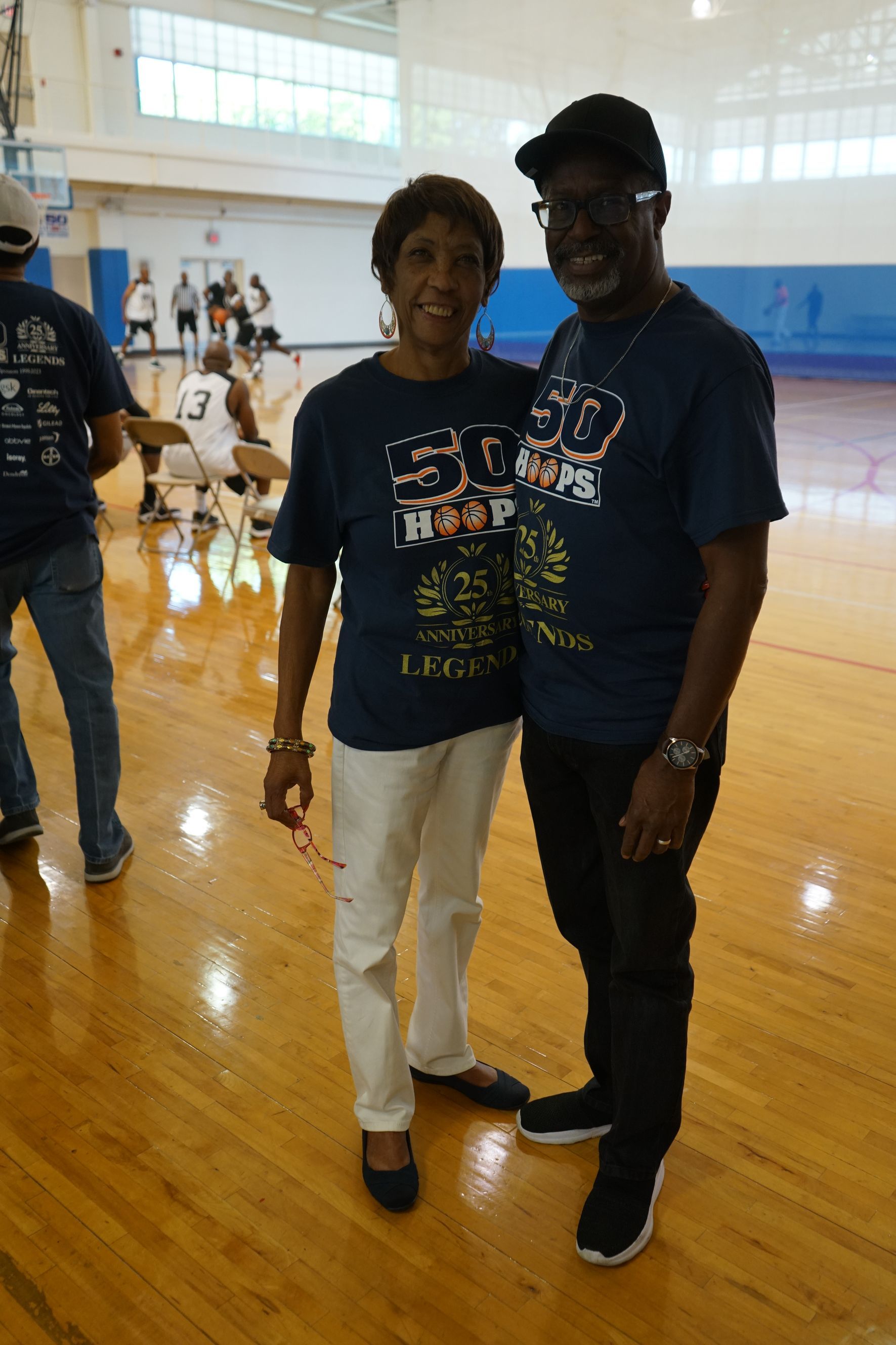 A smiling couple wearing matching blue shirts posing in a gymnasium.
