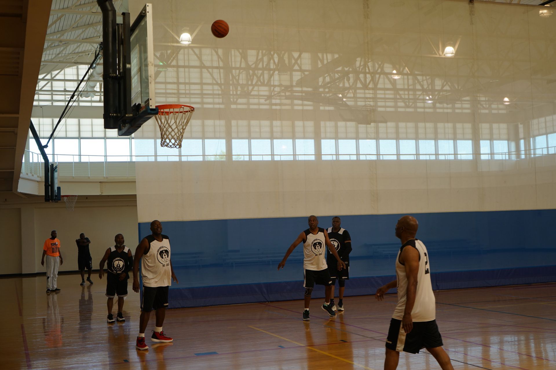 Basketball about to go into hoop; players on court.