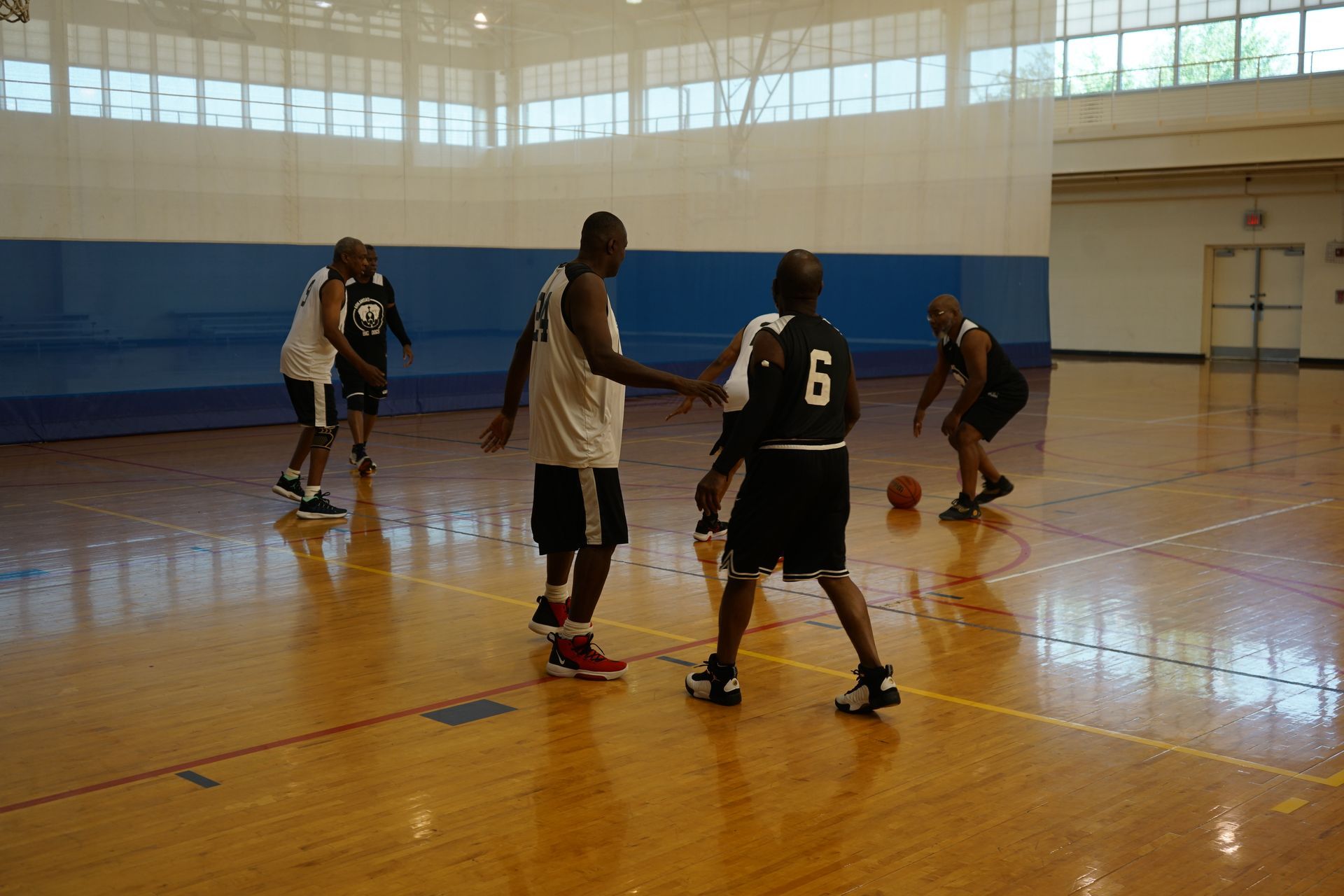 Basketball game in a gymnasium. Players in black and white uniforms dribble and prepare to play.