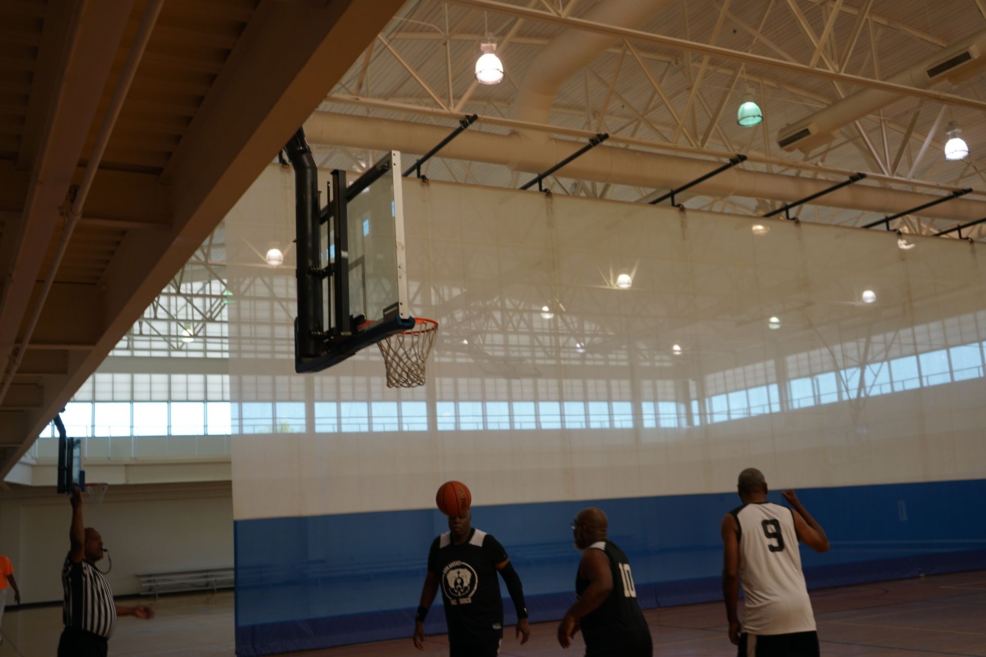 Basketball players shooting hoops in an indoor court.