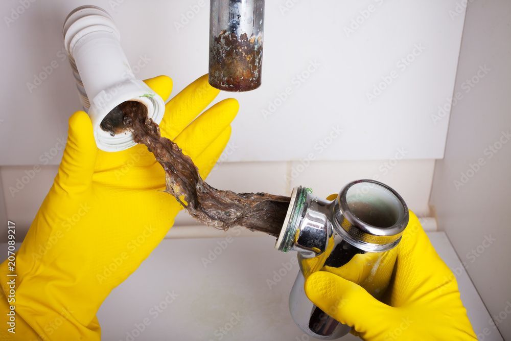 Shiny chrome plumbing under a dark-tiled sink.