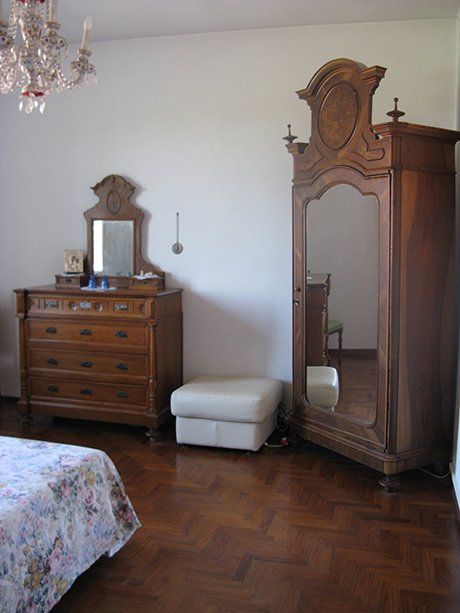 vista angolare di un letto di una stanza con armadio in legno, mensola in legno con tre cassetti e arredamento