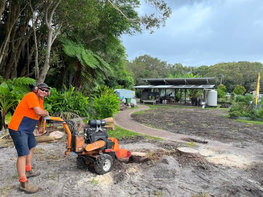 A Man Is Using A Stump Grinder To Remove A Tree Stump — Noosa Tree Stump Removal In Sunrise Beach, QLD