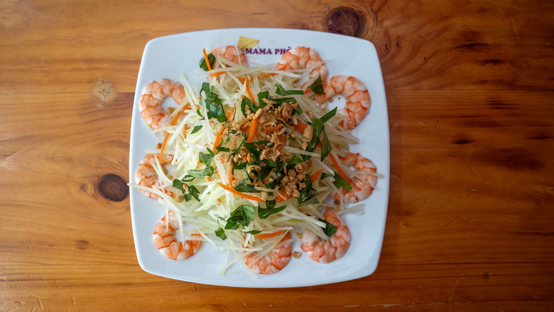 A white plate topped with shrimp and vegetables on a wooden table.