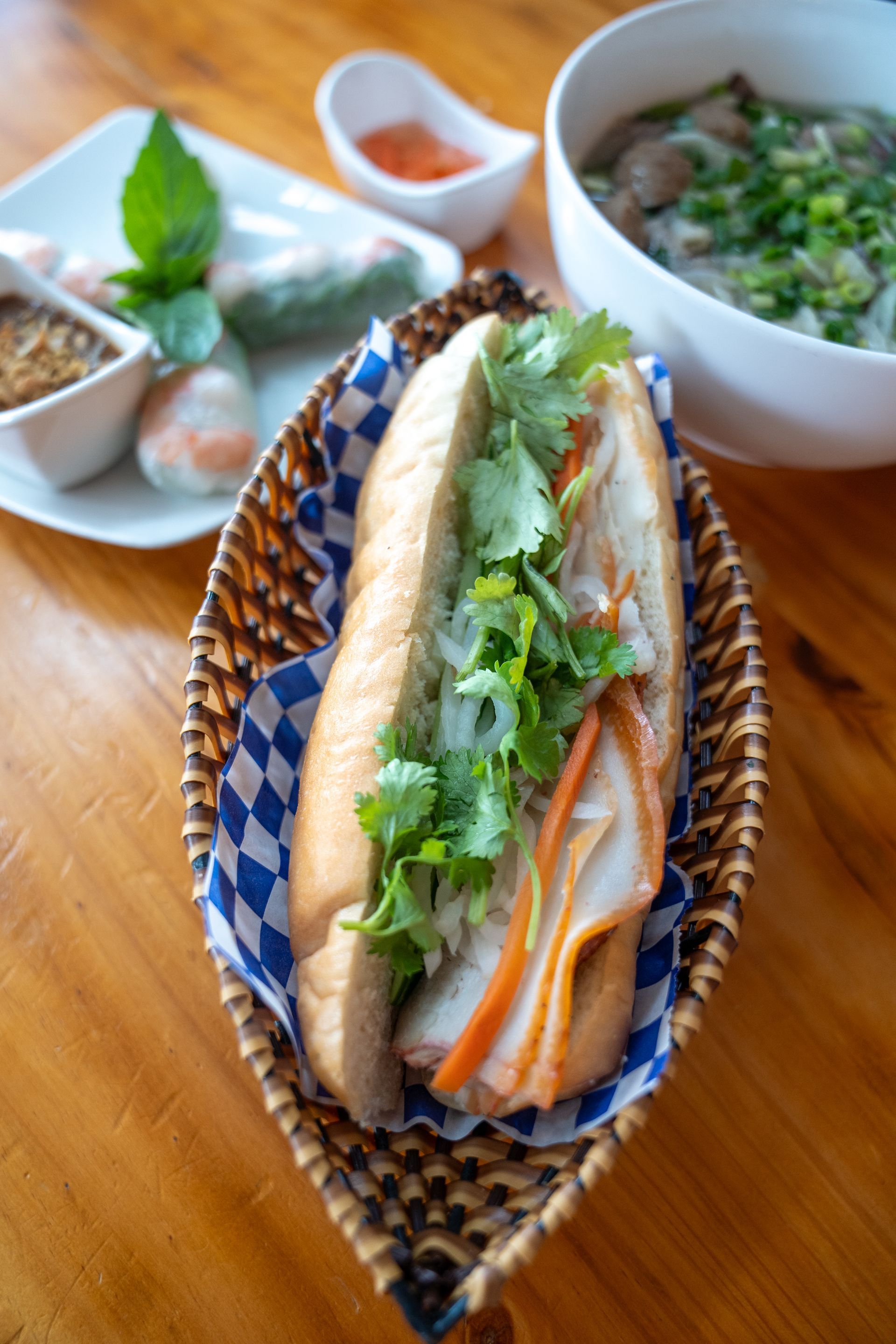 A sandwich and a bowl of soup are on a wooden table.
