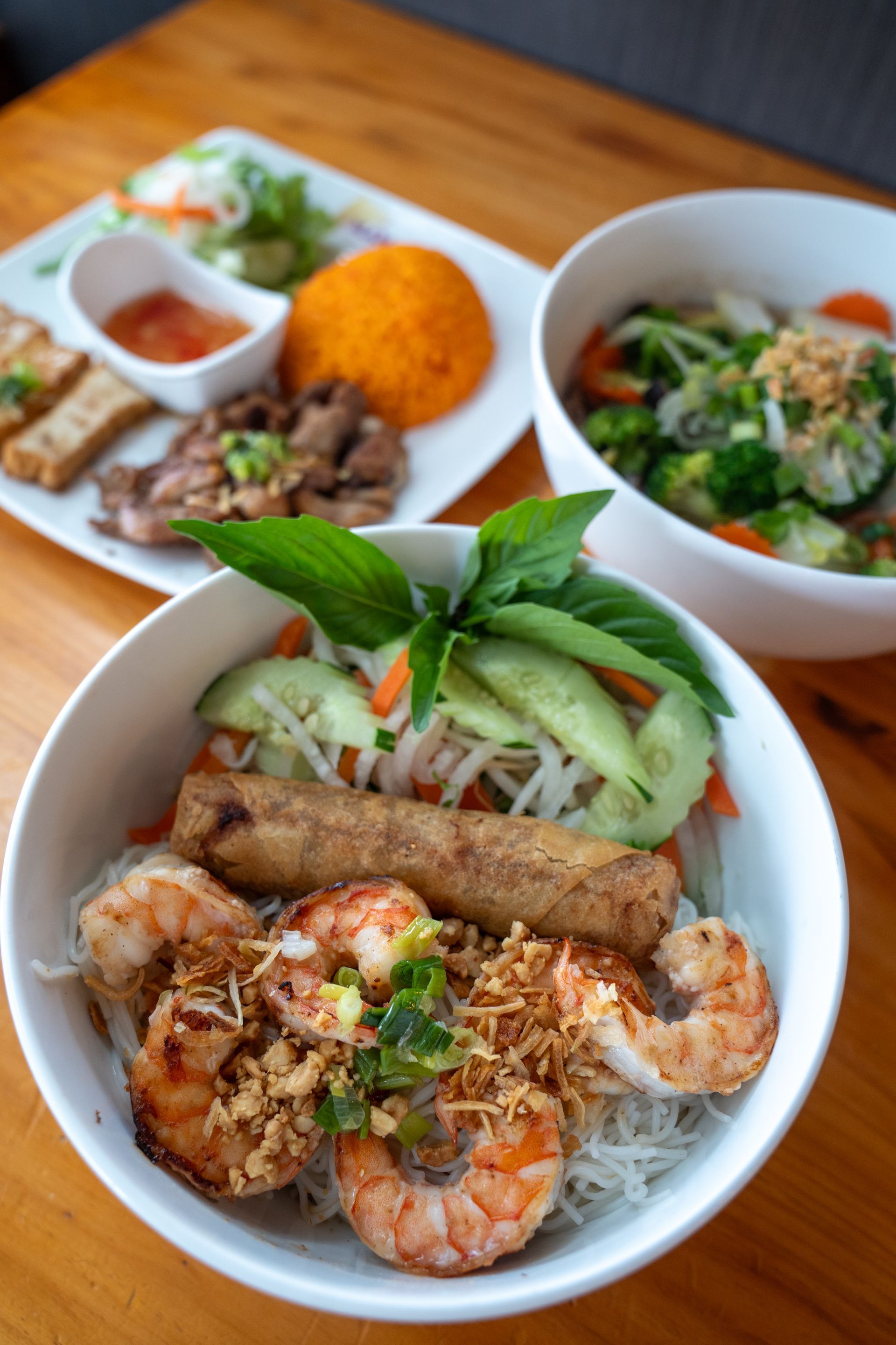 Three bowls of food are sitting on a wooden table.