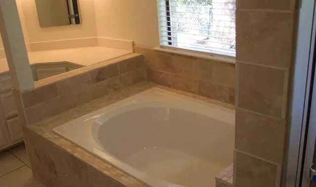 A bathroom with a bathtub, sink, mirror and window