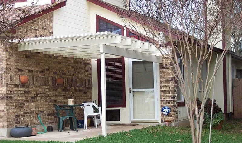 A brick house with a white pergola over the porch