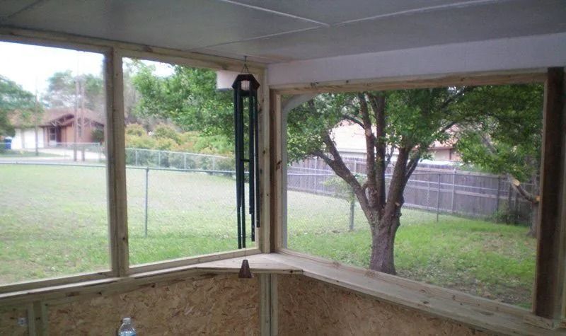 A screened in porch with a tree in the background.