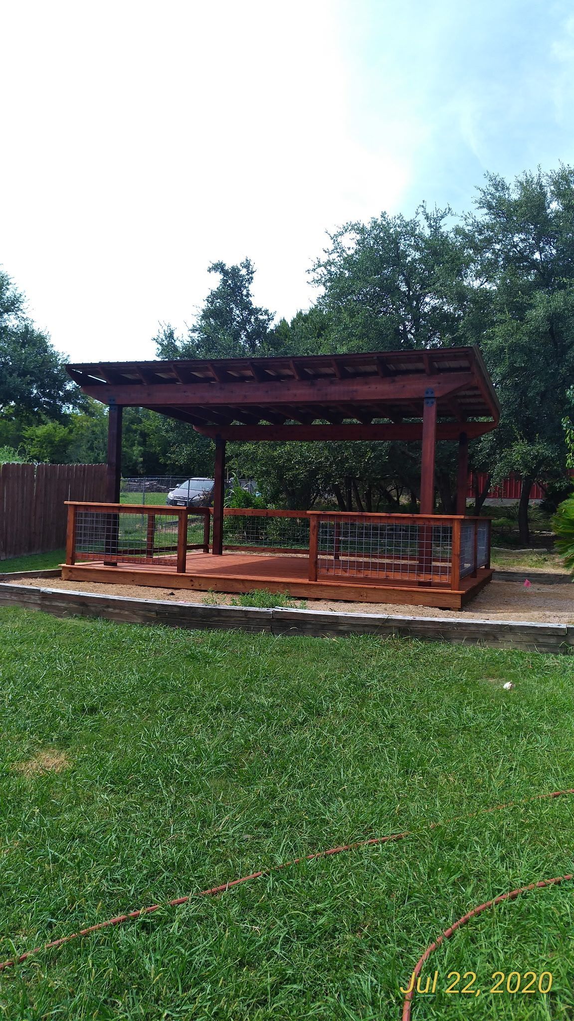 A wooden gazebo is sitting in the middle of a lush green field.