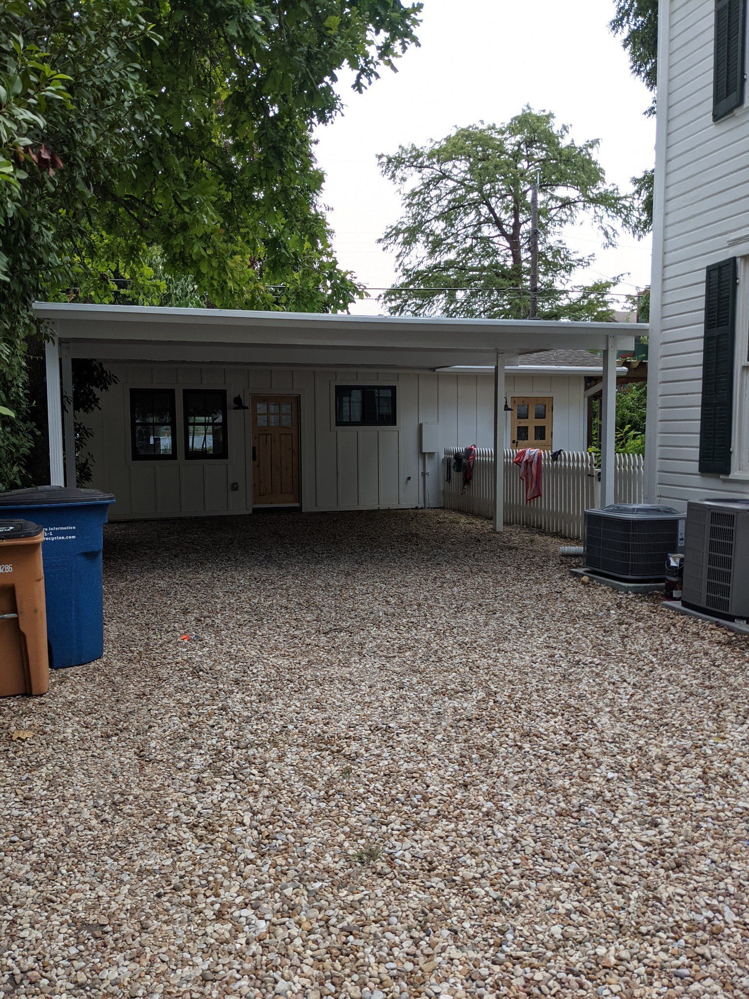 A gravel driveway leading to a white house