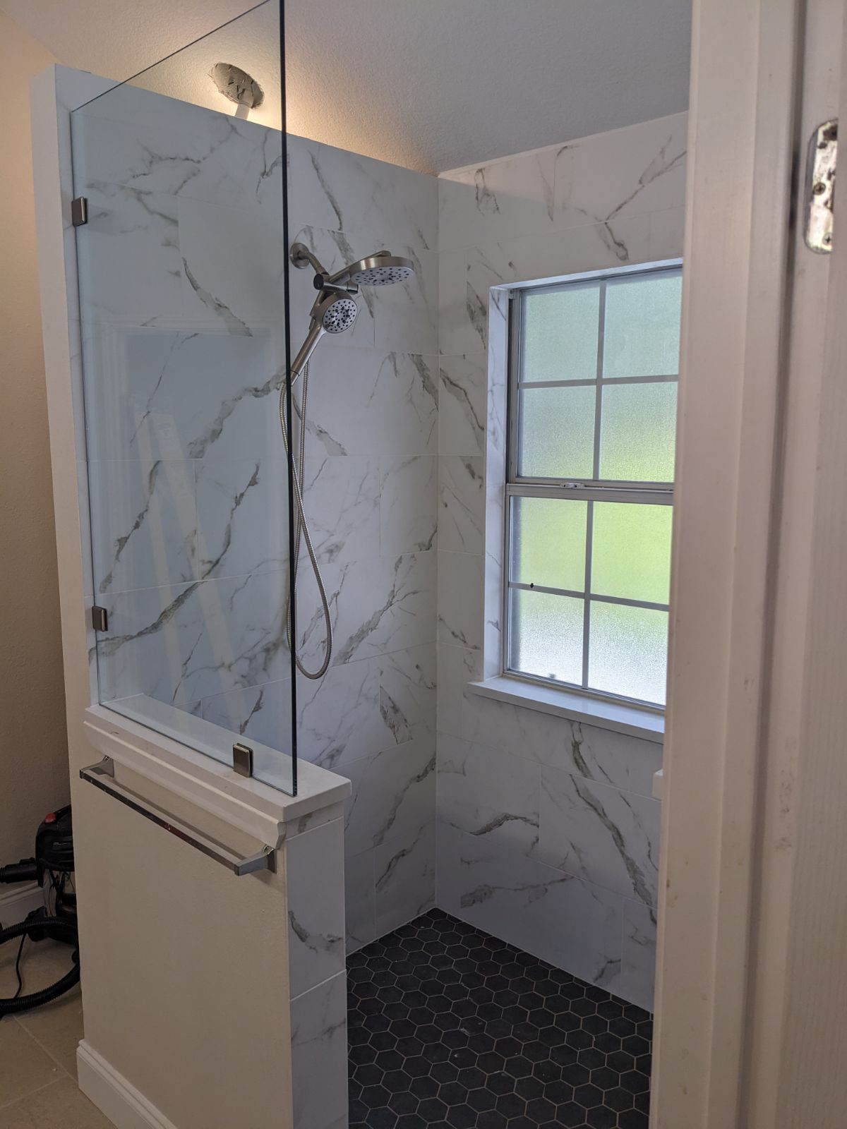 A bathroom with a walk in shower and a window.