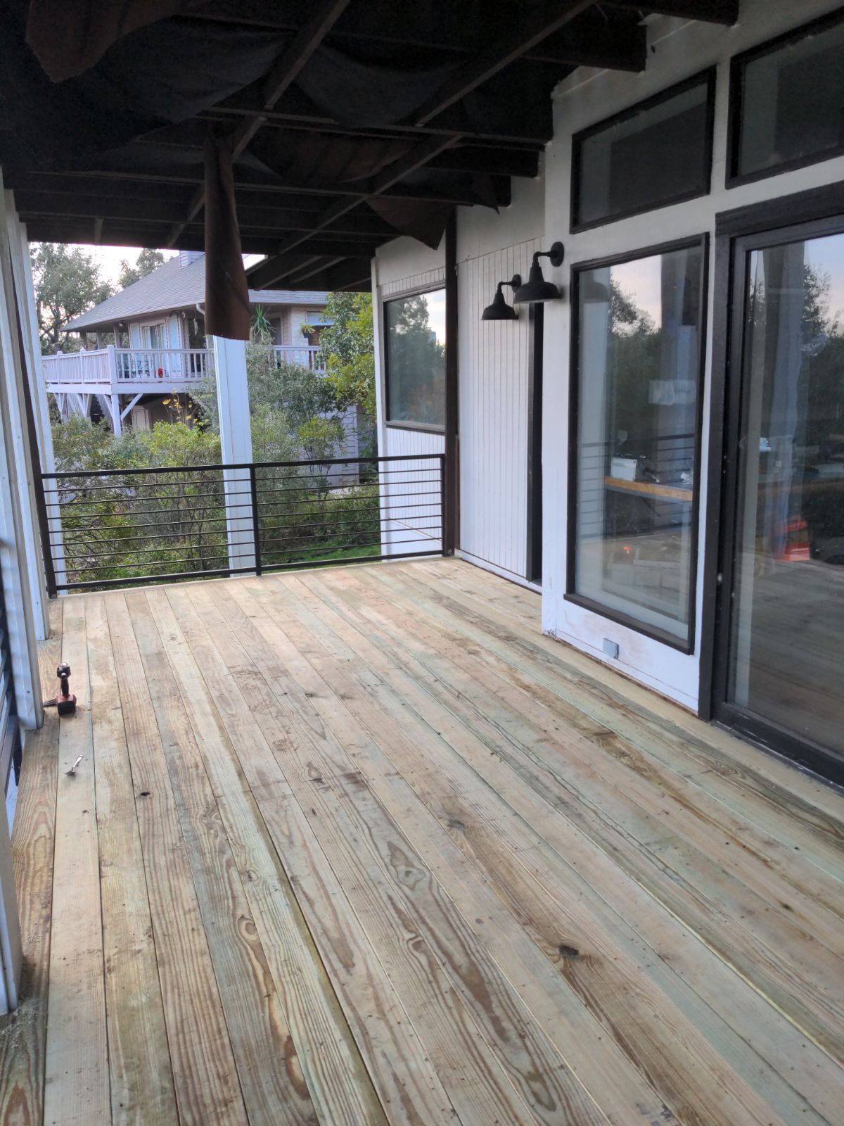 A large wooden deck with sliding glass doors and a railing.