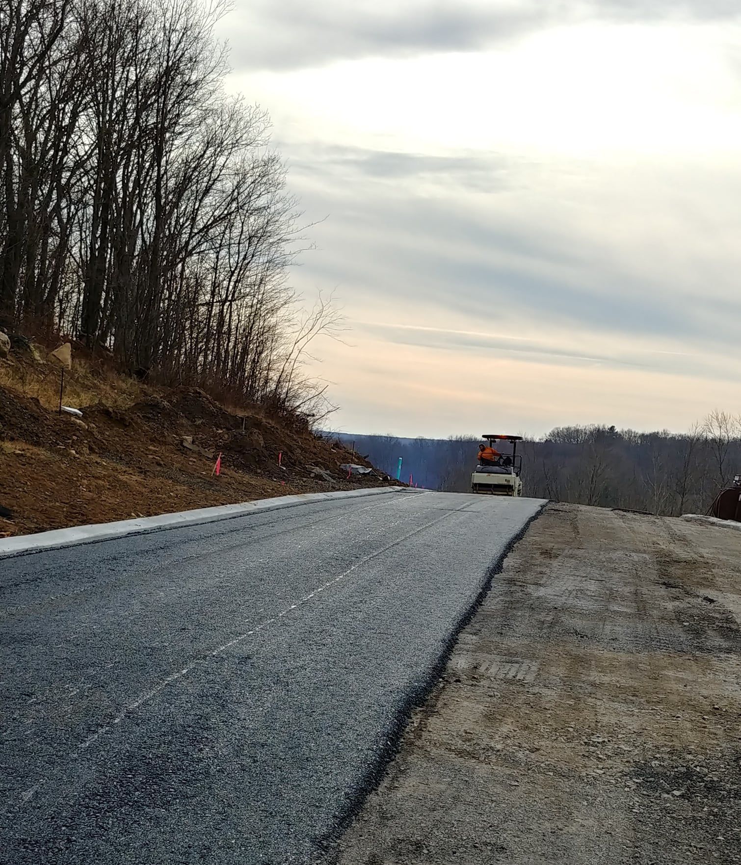 A truck is driving down a road with trees on the side.