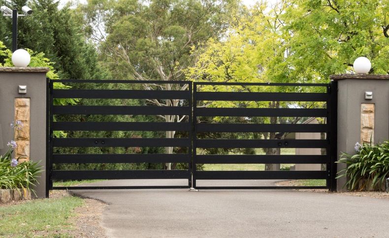 A wooden fence is surrounded by flowers and mulch in a backyard.