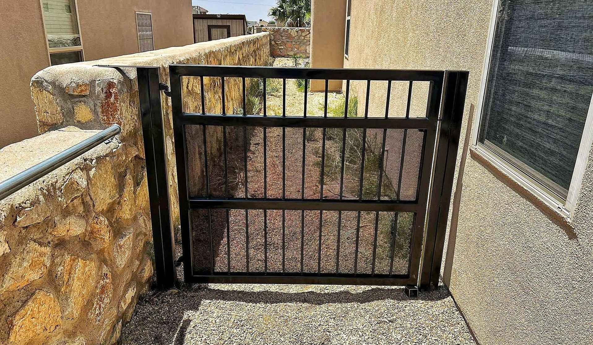 A chain link fence with a gate in the middle of a grassy field.