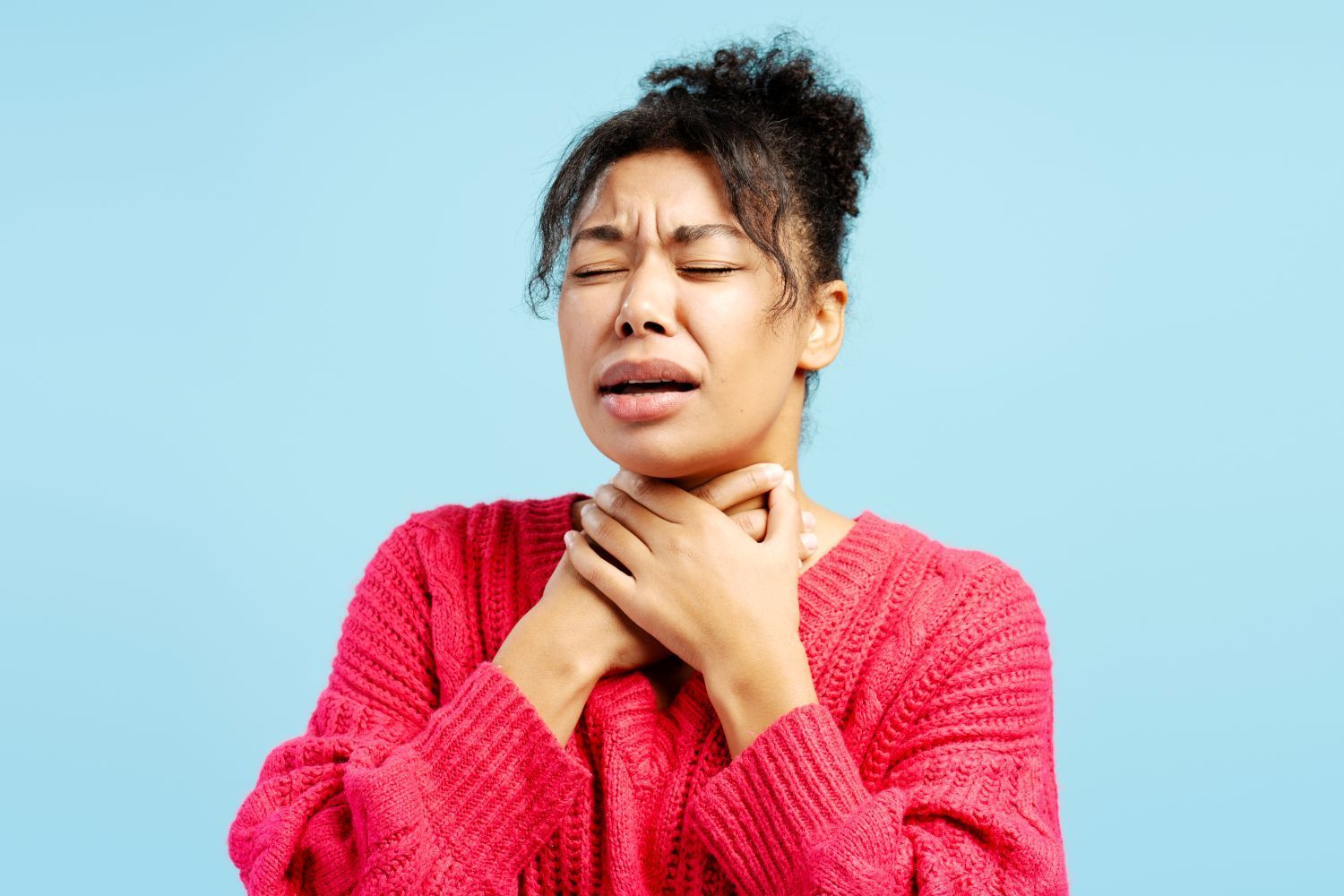A woman in a red sweater suffering from sore throat.