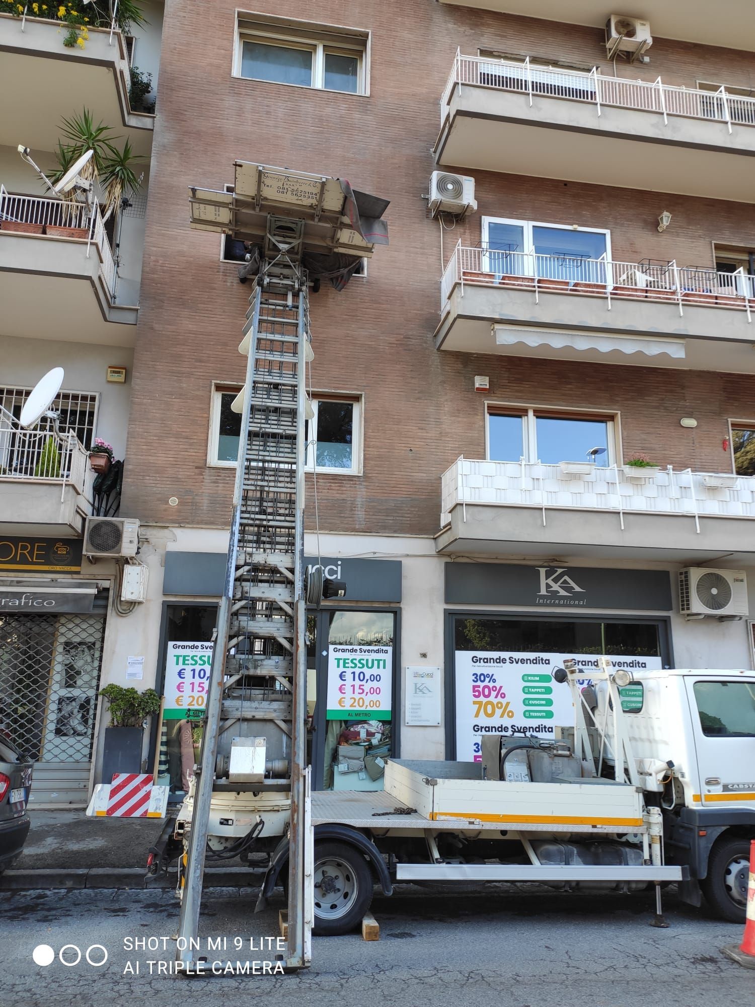Camion con sollevatore per spostare mobili accanto a un edificio.