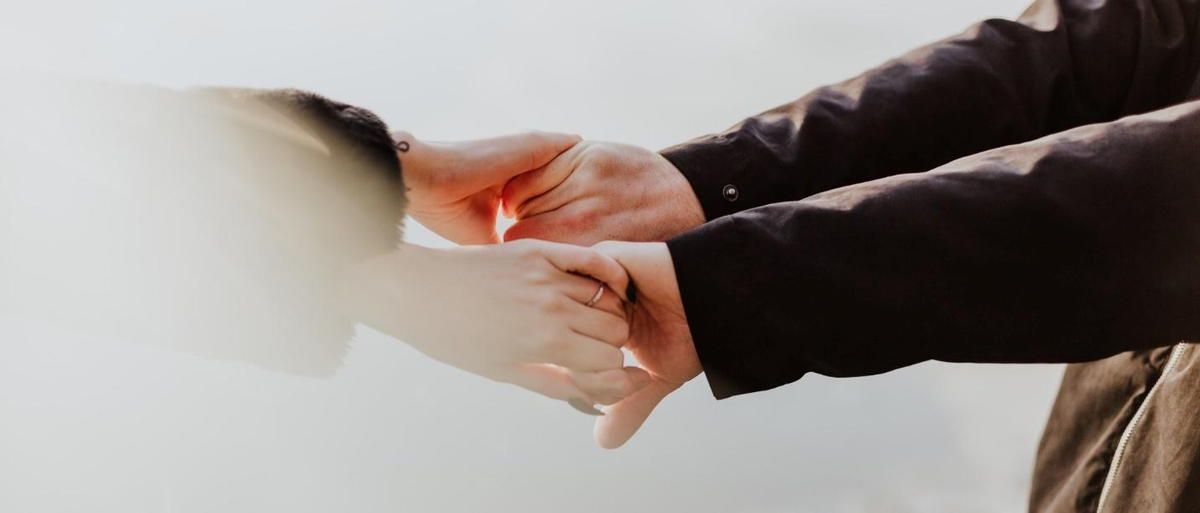 A close up of a person holding another person 's hand.