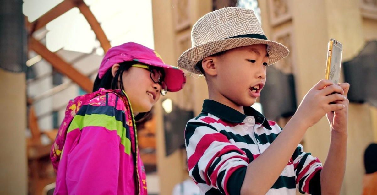 A boy and a girl are looking at a cell phone.