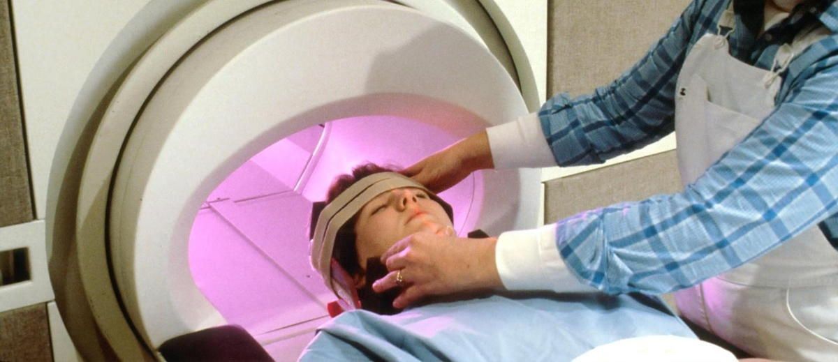 A person is laying in a machine with a bandage on their head.