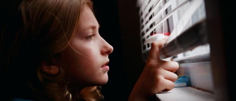 A young girl is looking out of a window.