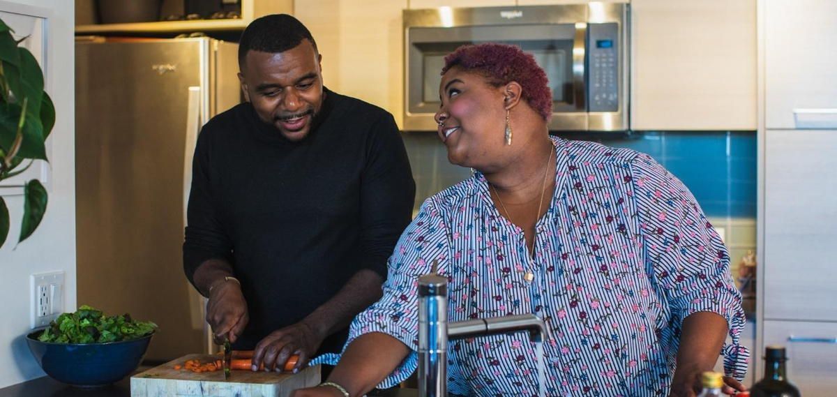 A man and a woman are cooking together in a kitchen.