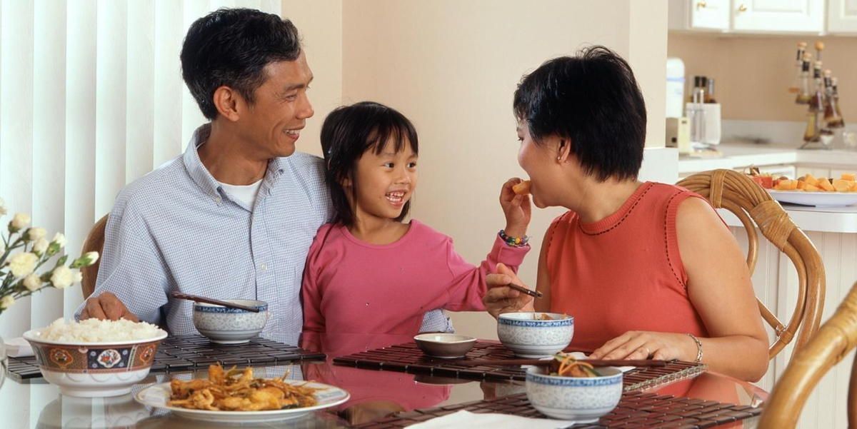 A family is sitting at a table eating food.