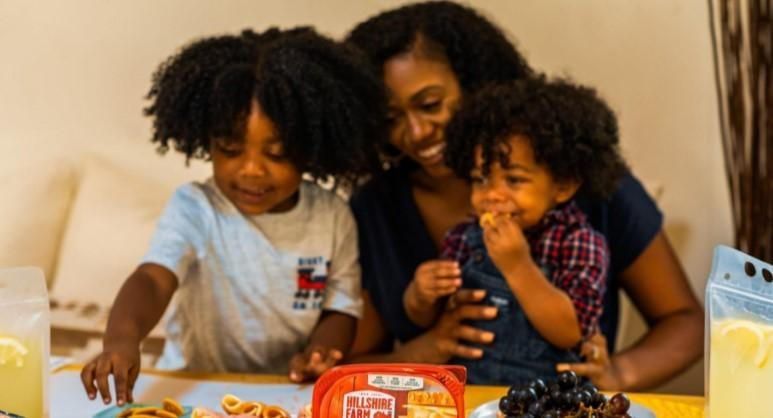 A woman and two children are sitting at a table eating food.