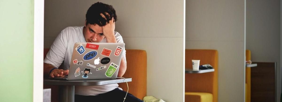 A man is sitting at a table using a laptop computer.